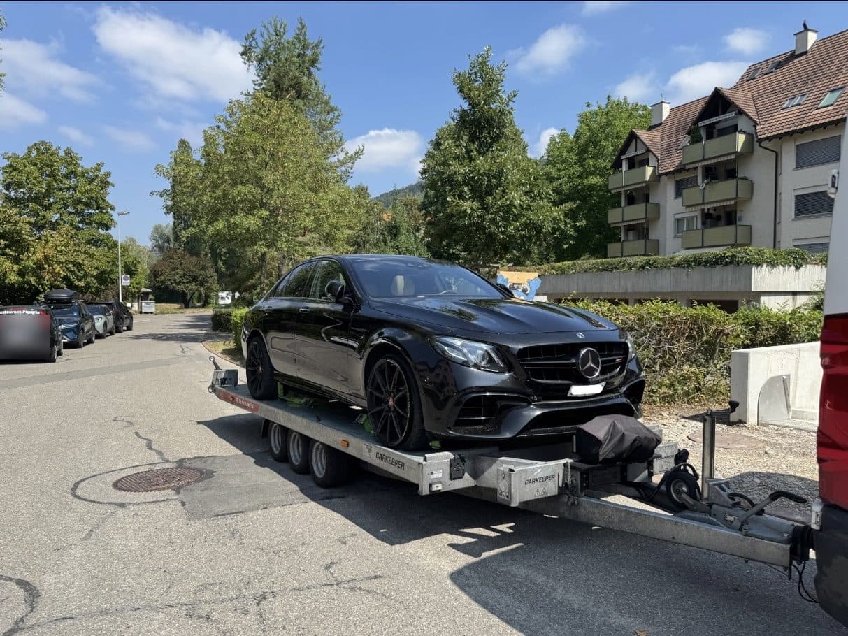Schwarze Mercedes-Limousine auf dem Anhänger in einem Wohnquartier