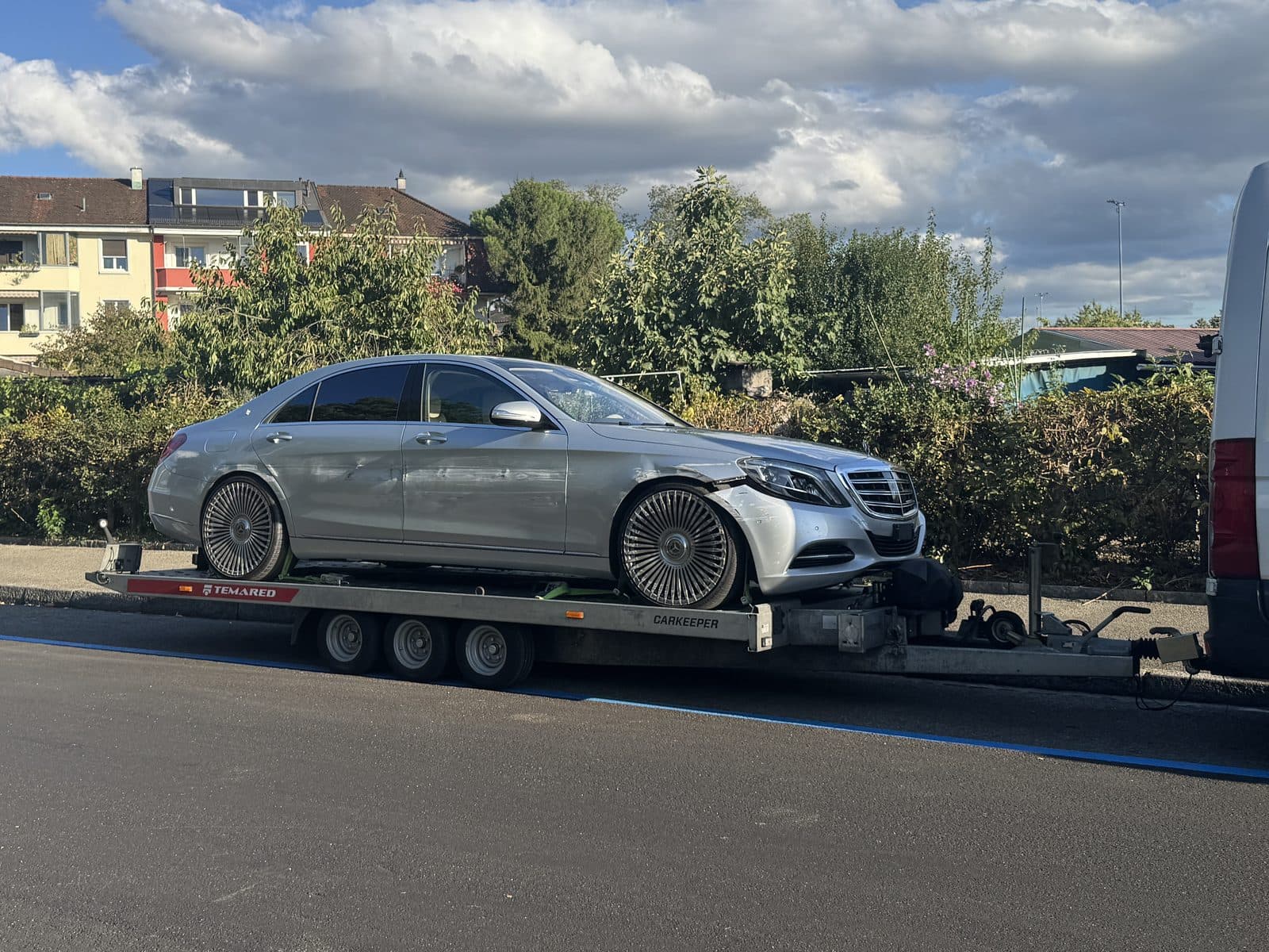 Silberne Mercedes-Limousine mit Unfallschaden an der Front auf dem Anhänger